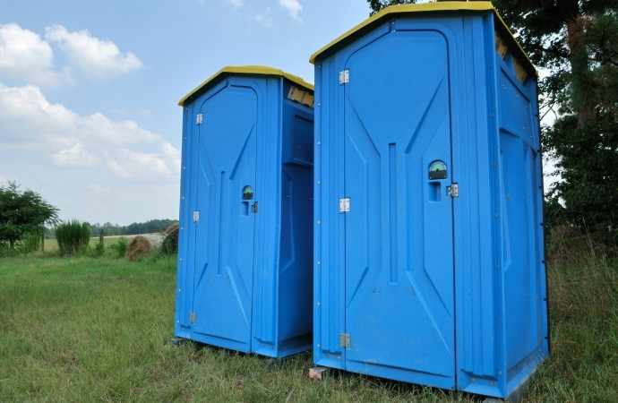 two portable toilets placed in a grass
