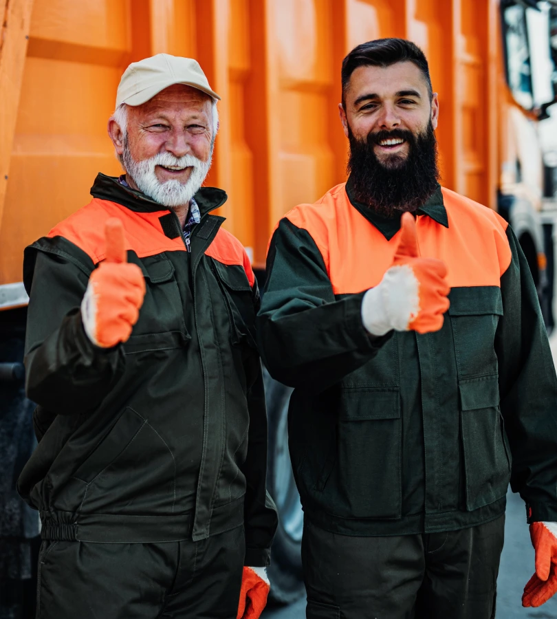 Senior and young garbage men working together on emptying dustbins for trash removal