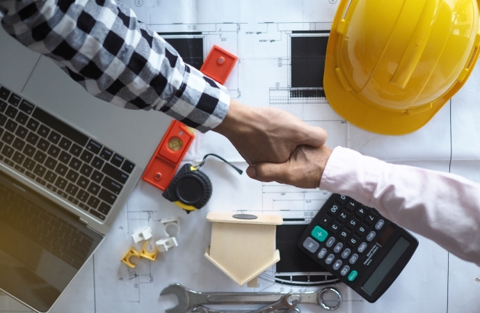 client and contractor handshaking on top of site plans